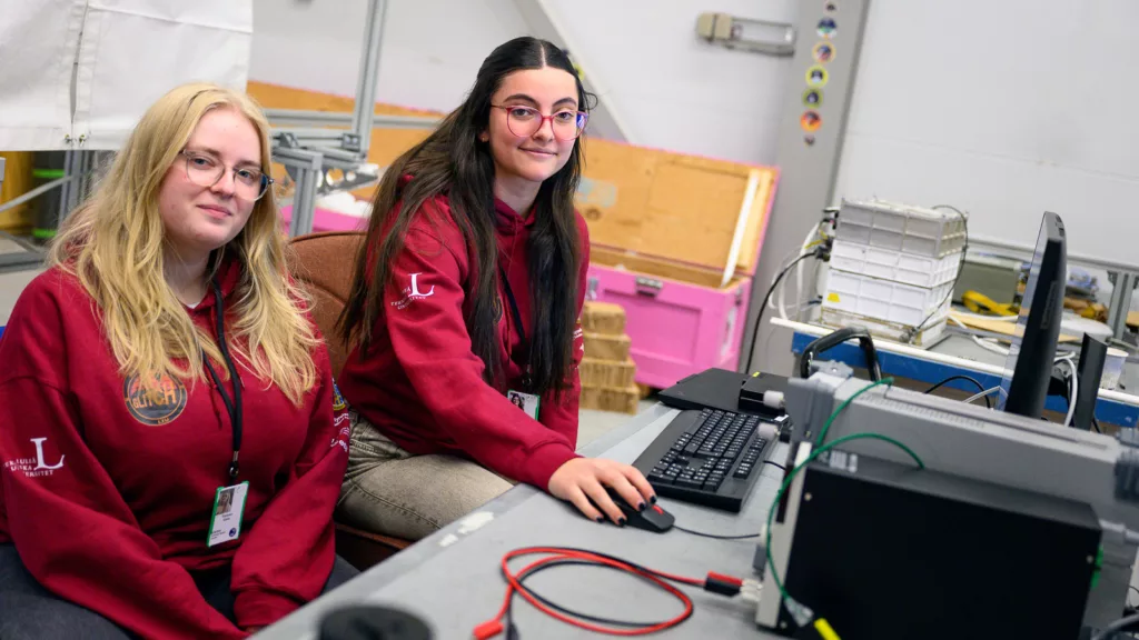 Two girls dressed in red sitting by a desk