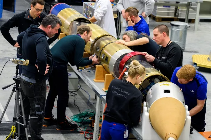 10 engineers working on a golden colored rocket payload
