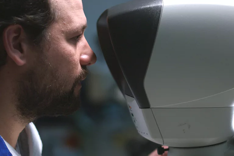 Space engineer looking into a microscope during the preparation of a space mission.