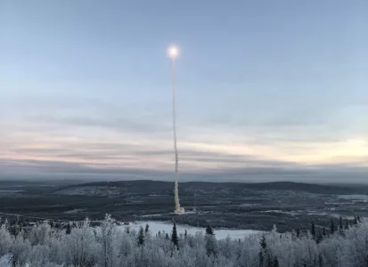 Launch of a science rocket photographed at a distance with snowy forests and mountains in the background
